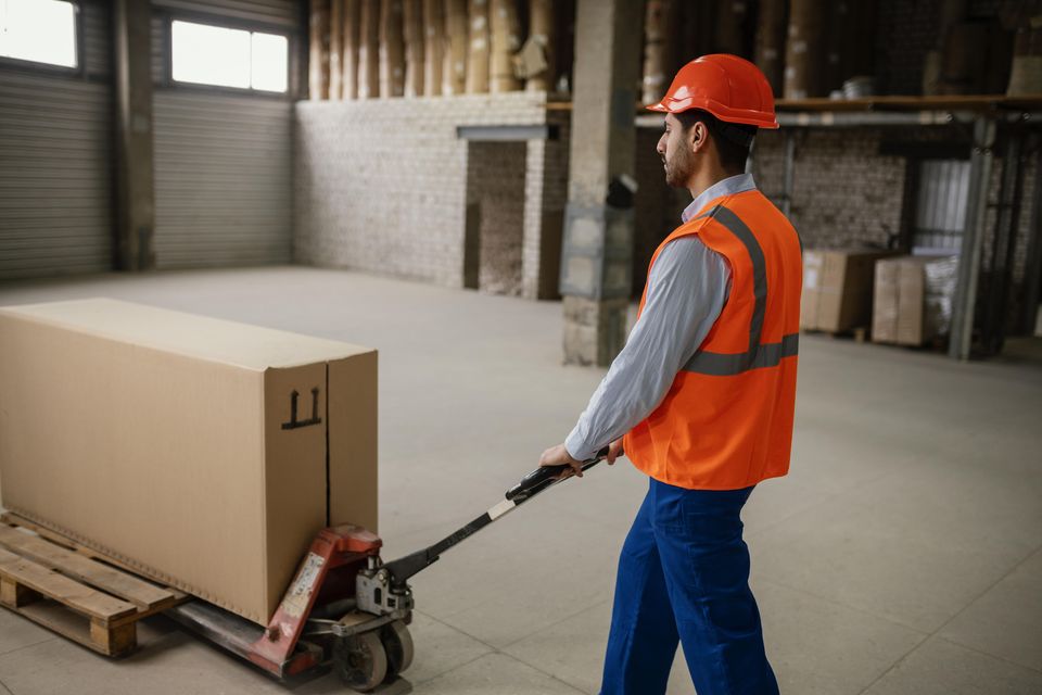 Trabajador levantando una caja pesada, análisis de factores de riesgo ergonómico