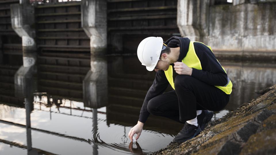 Ingeniera ambiental tomando una muestra de agua en campo